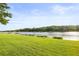 Expansive backyard with a serene lake view, lush green lawn, and benches to enjoy the natural surroundings at 1768 Lago Vista Blvd, Palm Harbor, FL 34685