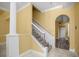 Bright foyer with elegant staircase, arched entryway, decorative columns, and a view into the home's interior at 1768 Lago Vista Blvd, Palm Harbor, FL 34685