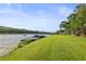 Beautiful waterfront with grassy lawn, mature trees, and a dock for easy water access at 1768 Lago Vista Blvd, Palm Harbor, FL 34685