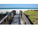 Wooden boardwalk leading to a pristine white sand beach with turquoise water and lush greenery at 1829 1St E Ave, Bradenton, FL 34208