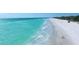 Aerial shot showcasing crystal-clear turquoise water meeting a beautiful white sand beach with people enjoying the scenery at 1829 1St E Ave, Bradenton, FL 34208