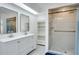 Bathroom featuring dual vanities, large mirrors, and a walk-in tiled shower with a built-in shelf at 18546 Kelly Rd, Spring Hill, FL 34610