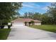 Ranch style home with mature landscaping, a two car garage, and a long driveway at 18546 Kelly Rd, Spring Hill, FL 34610