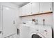 Bright laundry room with washer, dryer, wash sink, and storage cabinets at 18546 Kelly Rd, Spring Hill, FL 34610