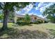 A side angle view of the home's exterior, showing lush greenery, mature trees, and a well-kept lawn at 2117 Laindale Pl, Valrico, FL 33596