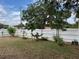 Spacious backyard featuring lush green grass, a white picket fence, and trees at 2213 Towering Oaks Cir, Seffner, FL 33584