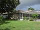 Exterior of home showcases a green lawn, screened-in pool area, and mature trees at 2213 Towering Oaks Cir, Seffner, FL 33584