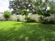 Well-maintained backyard with lush green grass, privacy fence, and mature trees and vegetation at 2213 Towering Oaks Cir, Seffner, FL 33584