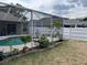 Backyard pool is surrounded by a screened lanai, garden beds, and a privacy fence at 2213 Towering Oaks Cir, Seffner, FL 33584
