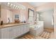 A relaxing main bathroom featuring a double vanity, a soaking tub, and a separate glass-enclosed shower at 2908 122Nd Pl E, Parrish, FL 34219