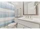 Bright bathroom with white vanity, quartz countertop, and blue striped shower curtain at 29895 Picana Ln, Wesley Chapel, FL 33543