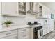 Bright kitchen featuring white cabinetry, stainless steel range hood, and subway tile backsplash at 29895 Picana Ln, Wesley Chapel, FL 33543