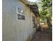 Side exterior featuring stucco, windows with bars, and natural climbing vines at 3503 N 11Th St, Tampa, FL 33605