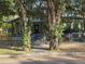 Charming bungalow with inviting front porch, framed by mature trees, enclosed with a metal chain-link fence at 3503 N 11Th St, Tampa, FL 33605