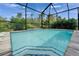 Swimming pool with blue tiled stairs in a screened-in lanai with lush landscaping at 3603 Woodmont Dr, Parrish, FL 34219