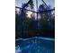 A screened-in pool area featuring evening lights, surrounded by lush trees, creates a relaxing outdoor experience at 3603 Woodmont Dr, Parrish, FL 34219