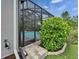 The back entrance to the screened in pool area is surrounded by lush green bushes at 3603 Woodmont Dr, Parrish, FL 34219