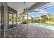 Covered patio showcases a patterned brick floor, ceiling fan, and view of the screened-in pool at 4690 Wrentham Pl, Palm Harbor, FL 34685