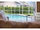 Inviting screened-in pool area, visible from the interior, features clear blue water and brick paver surround at 4690 Wrentham Pl, Palm Harbor, FL 34685