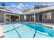 View of a screened-in pool, surrounded by a large patio and home exterior with multiple sliding glass doors at 4690 Wrentham Pl, Palm Harbor, FL 34685