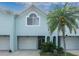 Inviting light blue two-story townhome with white garage doors, palm tree, and lush landscaping at 623 Garland Cir, Indian Rocks Beach, FL 33785