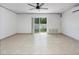 Bright living room features neutral tile flooring, a ceiling fan, and sliding glass doors leading to a backyard at 623 Garland Cir, Indian Rocks Beach, FL 33785