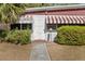 Charming entryway with a unique door and awning, surrounded by lush green bushes at 6427 15Th N St, St Petersburg, FL 33702