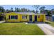 Charming yellow house with contrasting blue trim features a well-manicured front lawn at 6750 Hibiscus S Ave, South Pasadena, FL 33707
