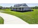 A charming single-Gathering home featuring a wraparound porch and a well-manicured lawn on a sunny day at 7627 Artifact Dr, Zephyrhills, FL 33541