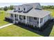 Inviting gray home with a charming wraparound porch, white railings and dormer windows at 7627 Artifact Dr, Zephyrhills, FL 33541