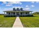Charming single Gathering home featuring a wraparound porch, well-manicured lawn, and inviting curb appeal at 7627 Artifact Dr, Zephyrhills, FL 33541
