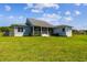 Back exterior view of the home with a screened porch and lush green lawn at 7627 Artifact Dr, Zephyrhills, FL 33541