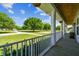 Relaxing wraparound porch view with white columns, lush lawn, and mature trees at 7627 Artifact Dr, Zephyrhills, FL 33541