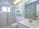 Bathroom featuring colorful wallpaper, a shower with sliding glass doors, white cabinetry, and a sink with a mirror at 8064 Brentwood Rd, Seminole, FL 33777
