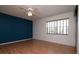 Bedroom featuring beautiful laminate wood flooring, blue accent wall, and natural light at 8064 Brentwood Rd, Seminole, FL 33777