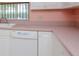 Kitchen with white cabinets and appliances with pink countertops offers a charming and functional space at 8064 Brentwood Rd, Seminole, FL 33777