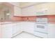 Bright kitchen with white appliances and cabinets and light pink countertops provides a clean and functional space at 8064 Brentwood Rd, Seminole, FL 33777