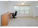 Bright office space featuring a built-in desk, a large window with blinds, and neutral carpet at 8064 Brentwood Rd, Seminole, FL 33777