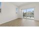 Bright living room with neutral paint, wood-look floors, and sliding glass door to balcony at 8848 Moonlit Meadows Loop, Riverview, FL 33578