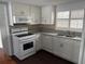 Well-lit kitchen featuring white cabinetry, tile backsplash, and stainless steel sink at 10208 Oak Hill Dr, Port Richey, FL 34668
