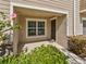 Inviting covered front porch entrance with decorative shrubbery, muted brown siding, and a white trimmed window at 10436 Rivercrest Dr, Riverview, FL 33578