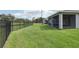 A lush green backyard enclosed by a black fence, offering scenic views of a pond at 10736 Whitland Grove Dr, Riverview, FL 33578