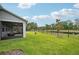 Spacious backyard featuring a well-manicured lawn, a screened lanai, a black fence, and a peaceful pond view at 10736 Whitland Grove Dr, Riverview, FL 33578