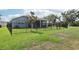 Green backyard with black fence and a view of the screened in porch overlooking a pond at 10736 Whitland Grove Dr, Riverview, FL 33578