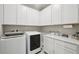 Well-equipped laundry room with modern washer and dryer, ample storage cabinets, and a convenient countertop workspace at 10736 Whitland Grove Dr, Riverview, FL 33578