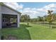 Lush backyard with black fence, porch with ceiling fans, overlooking a serene pond at 10736 Whitland Grove Dr, Riverview, FL 33578