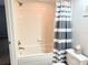 Tiled bathtub with shower, shower caddy and blue and white striped shower curtain at 11351 Shipwatch Ln # 1844, Largo, FL 33774