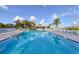 Refreshing community pool reflecting the blue sky, lined with lounge chairs and palm trees at 11351 Shipwatch Ln # 1844, Largo, FL 33774
