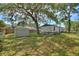 Large backyard with mature trees, shed, and side view of the home at 11940 Terra Ceia Ave, New Port Richey, FL 34654