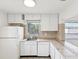 Bright kitchen with white cabinets, stainless steel sink, and ceramic tile countertops at 128 Brandy Wine Dr, Largo, FL 33771
